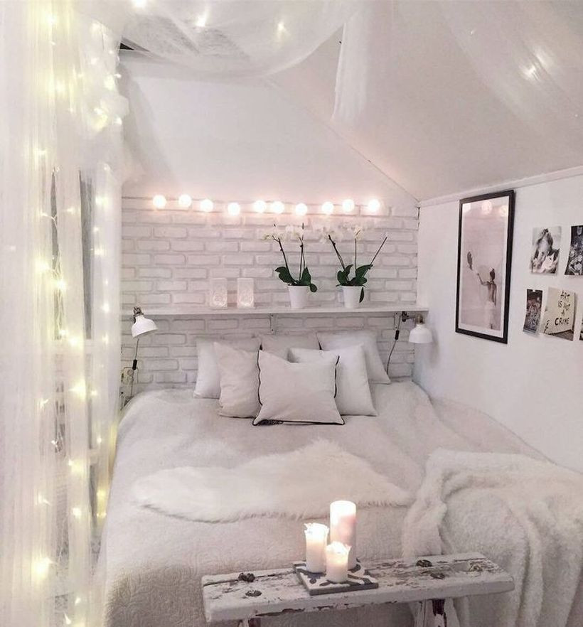 Best girls room decoration with white furry blankets, small white pillows, white walls, hanging string lamps and wooden rack on the wall
