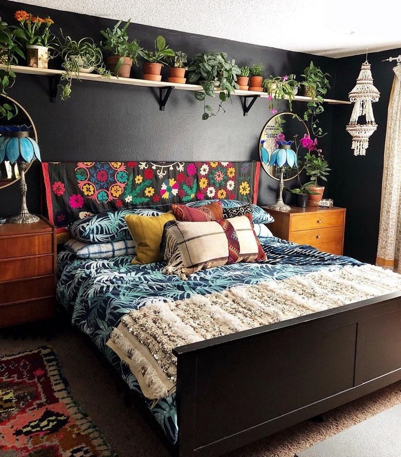 Boho bedroom style with plant patterns on black blankets, combined colorful pillows, carpet patterns, shelves on plant mattresses, brown storage cabinets, white chandelier ornaments