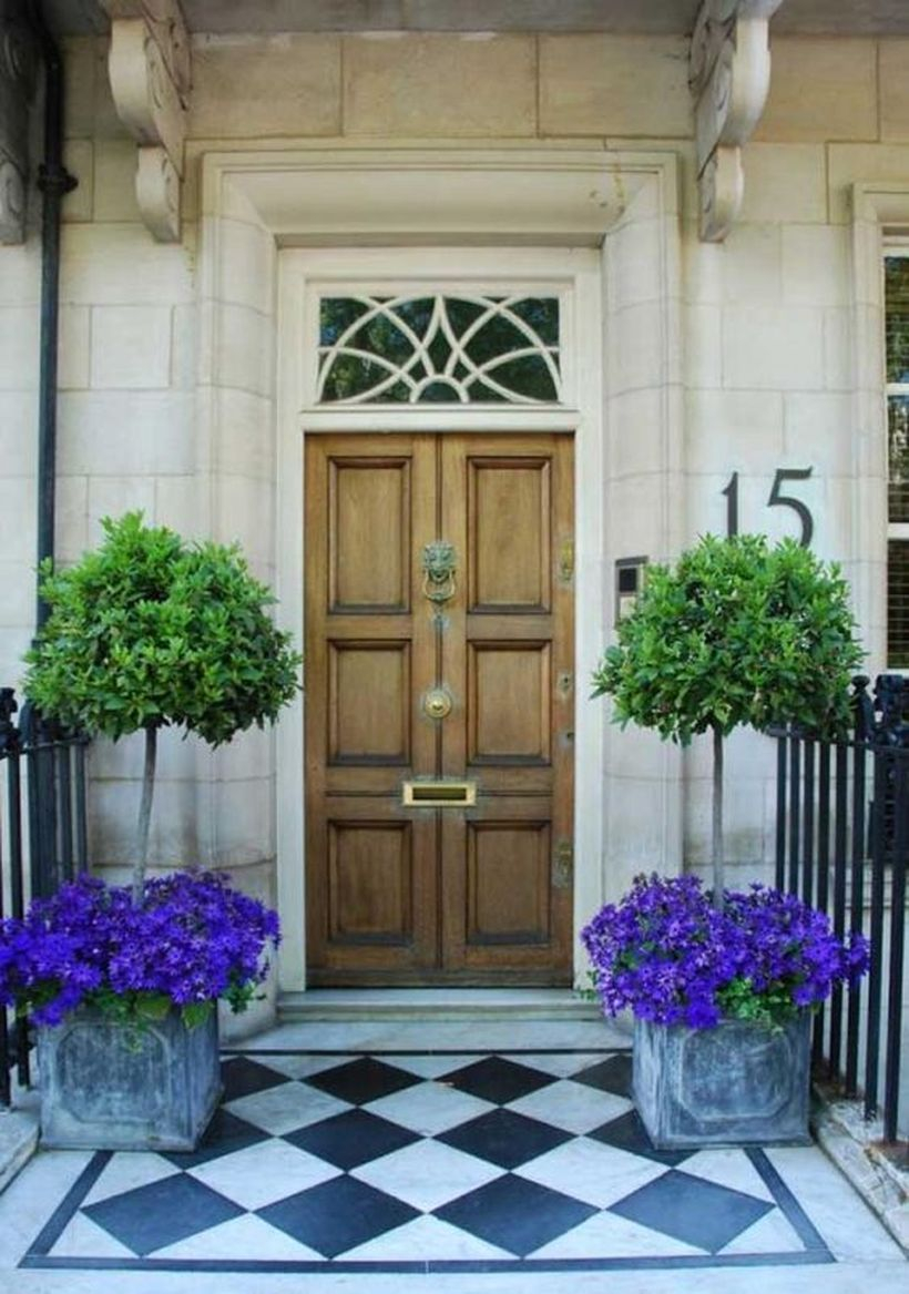 Front door decoration with purple bloom and small tree in concrete box planter