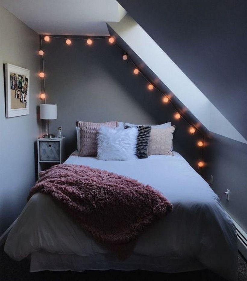 Modern girls room decor with white mattress, colorful pillows, pink blanket, storage and white lights in the corner and string lamp decorations
