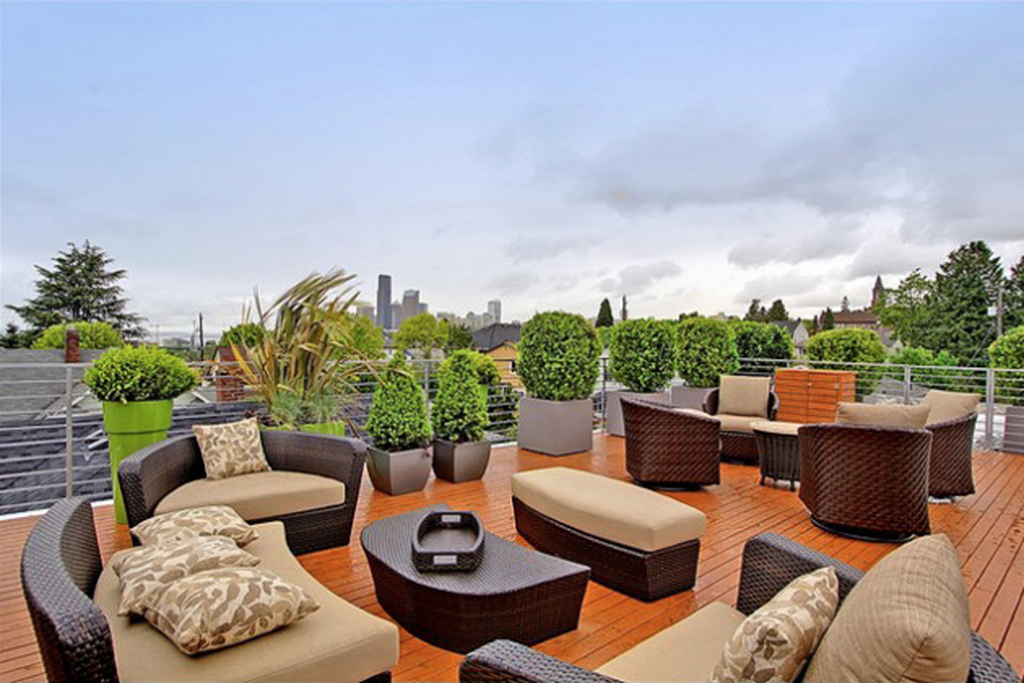 Modern small rooftop design with rattan seating combined with wooden floor and plants around it to perfect your rooftop garden