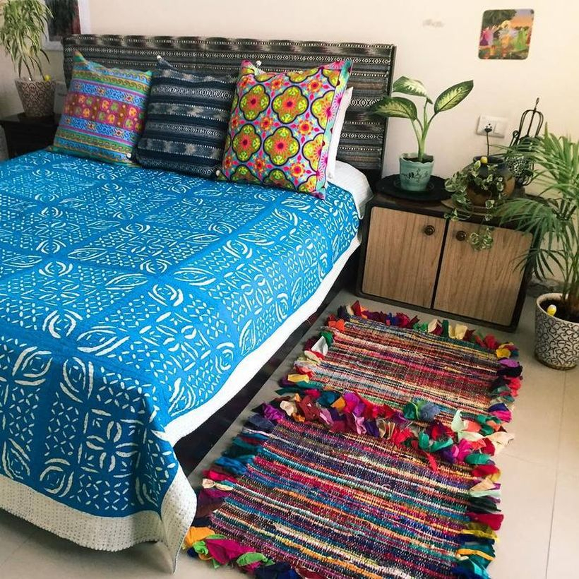 Stunning boho bedroom style blue blanket with white pattern, colorful pillow and colorful striped carpet to look beautiful