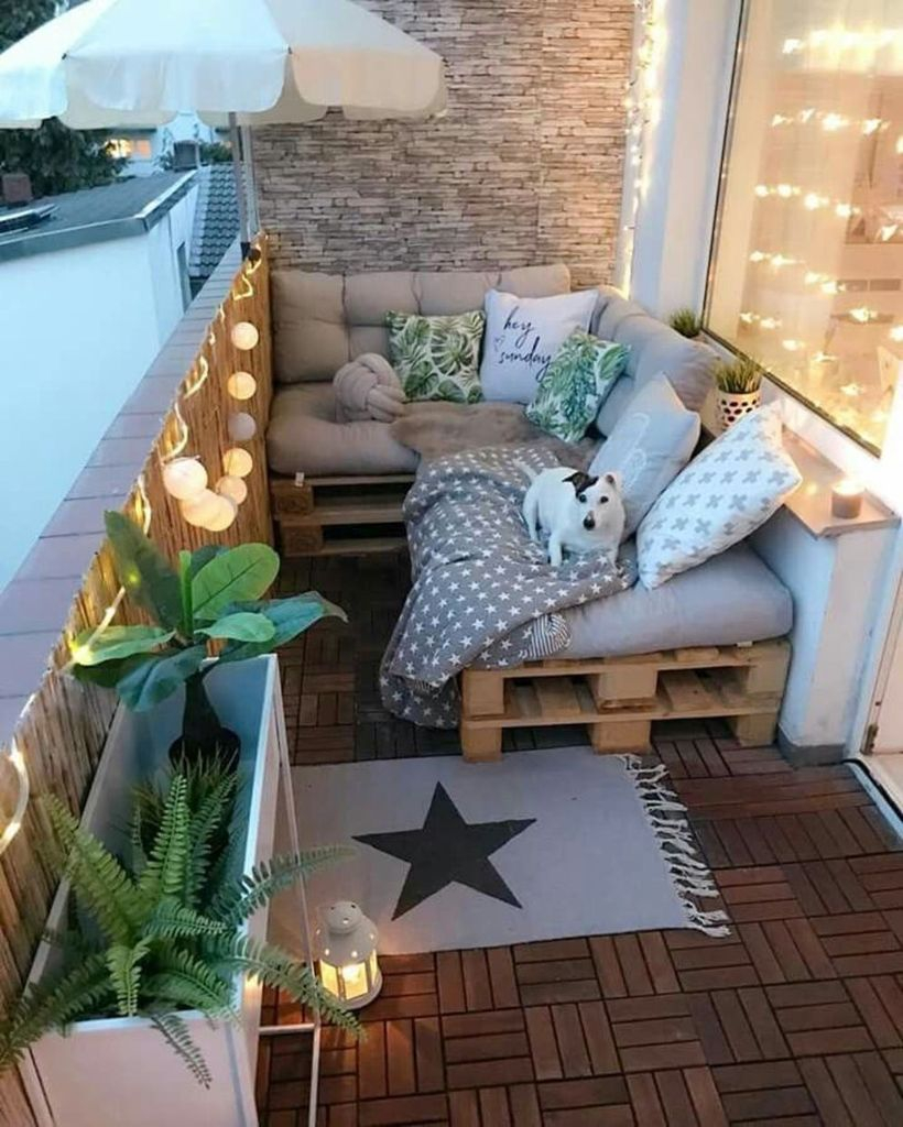 Wooden floor and pallet sofas combined with string lamps for balcony