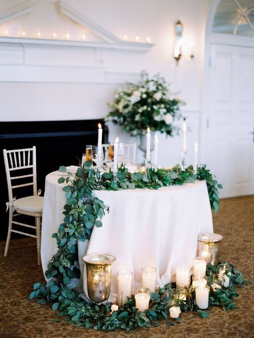Romantic sweetheart table with lush greenery accents and a grouping of candles
