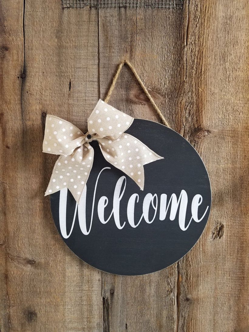Simple front door decoration with welcome sign from round wooden hang on the door