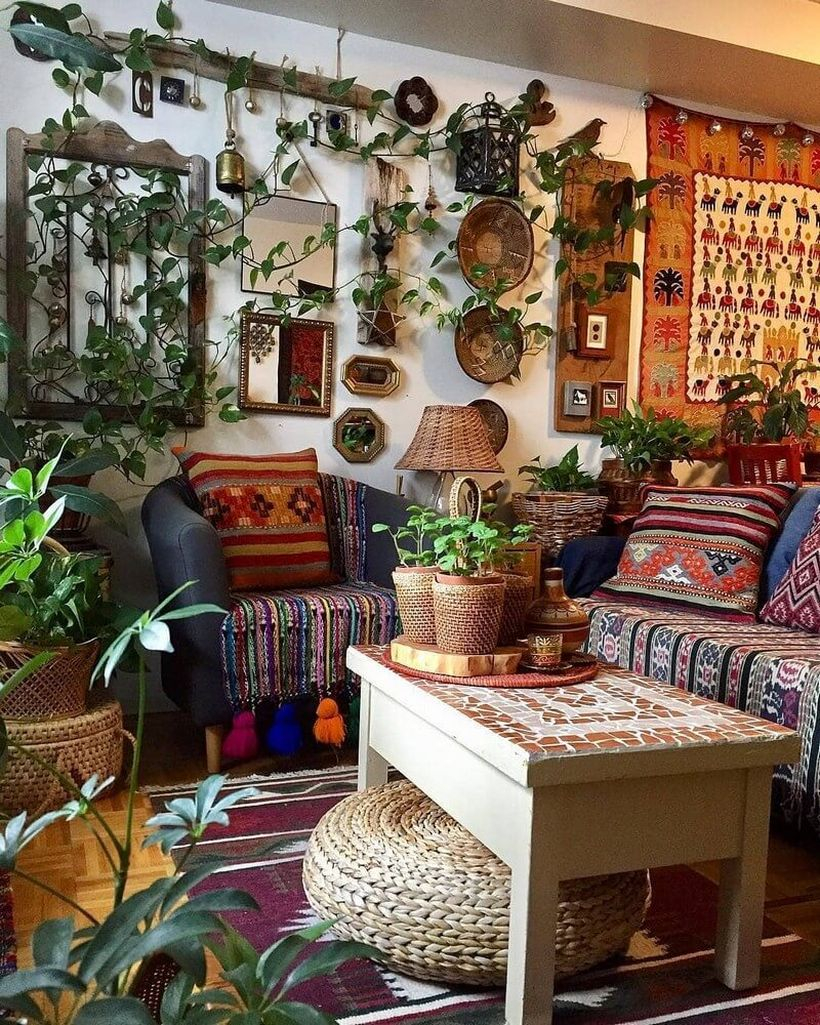 Best boho living room design with blue sofa combined striped fabric, unique patterned sofa cushions, patterned rugs in red hearts, colorful wall art patterned fabric, greenery climbing on the walls and white square tables