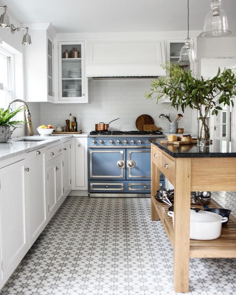 A small sun-patterned kitchen floor on a white floor with a white cabinet and wooden table to look simple