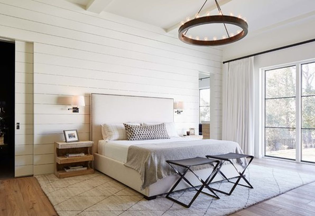 An awesome white bedroom with white bed, wooden chairs, white wooden walls and round wooden candle lamps