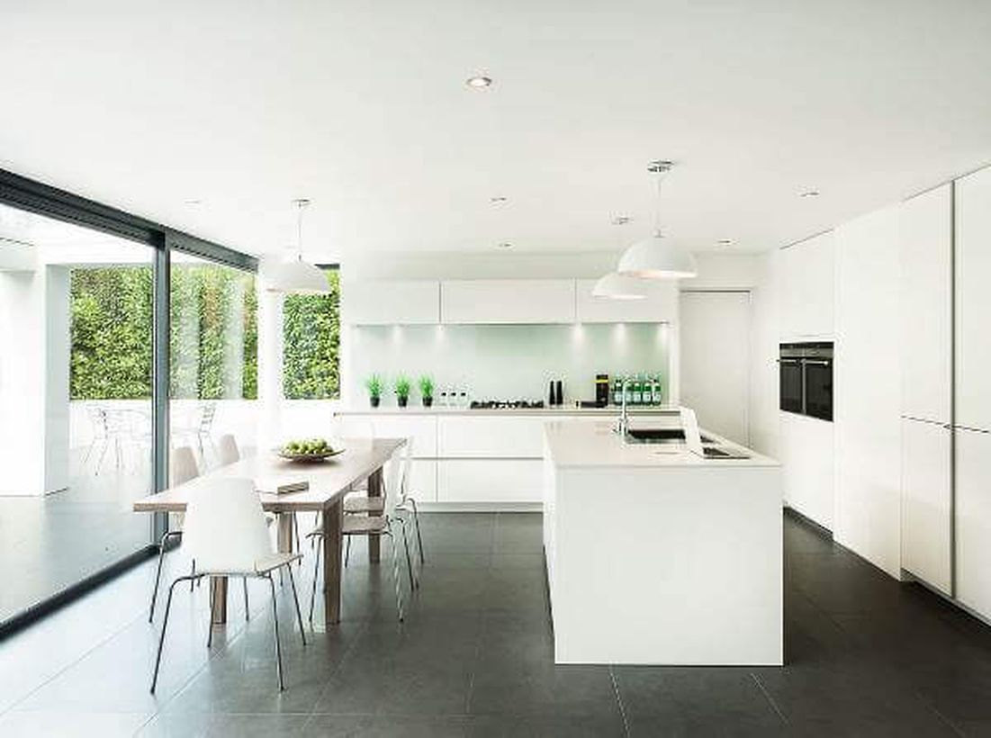 Black kitchen flooring with white island table, white cabinet, wooden table, and white chairs to look beautiful