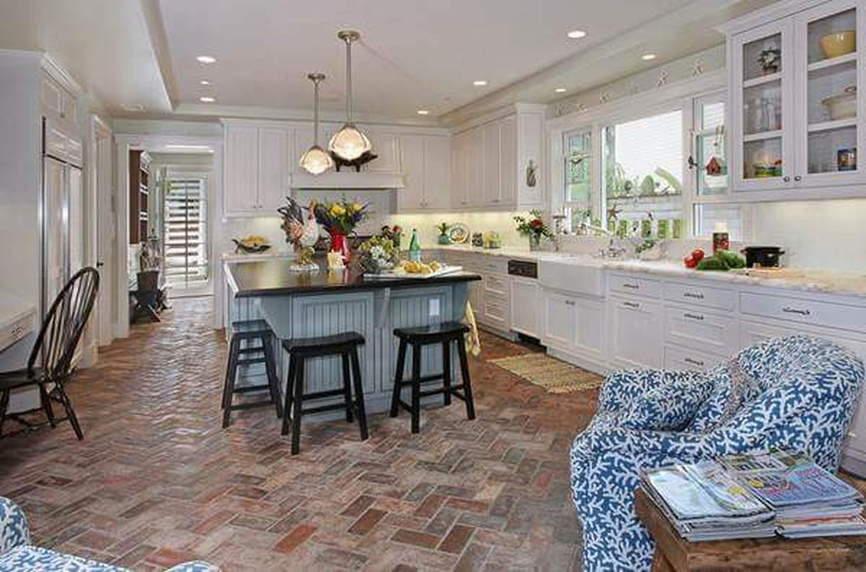 Classic brick kitchen floor with white cabinet, blue island table from wood and modern hanging lamps decoration