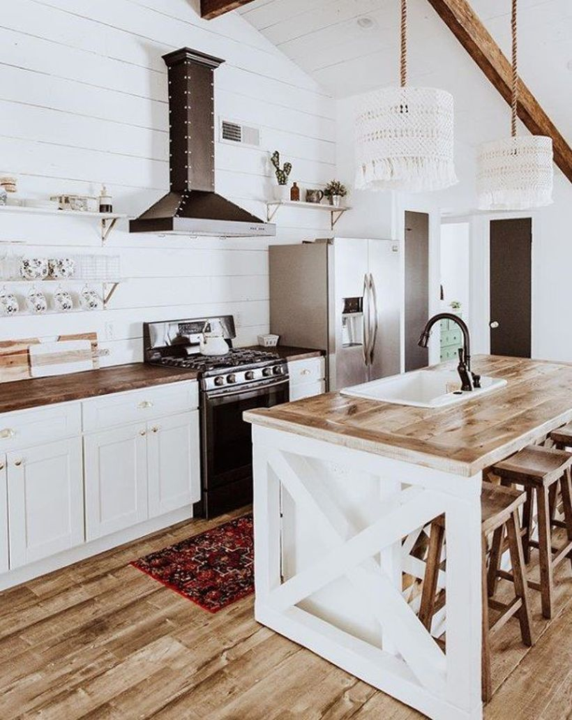 White kitchen with white hanging plants, wooden table and white cabinet to look stunning