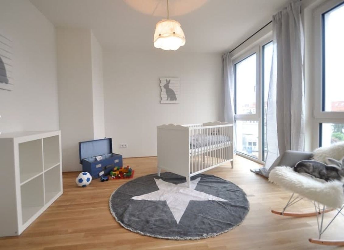 Large-monochrome-baby-boys-nursery-room-with-white-wooden-bed-big-rug-start-patterned-for-childrens-play-grounding