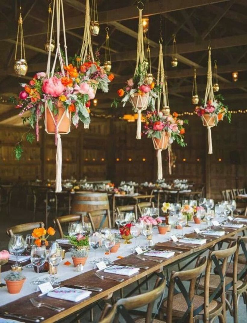 Potted blooms and greenery plus hanging planters with colorful flowers over the table make it bright and boho