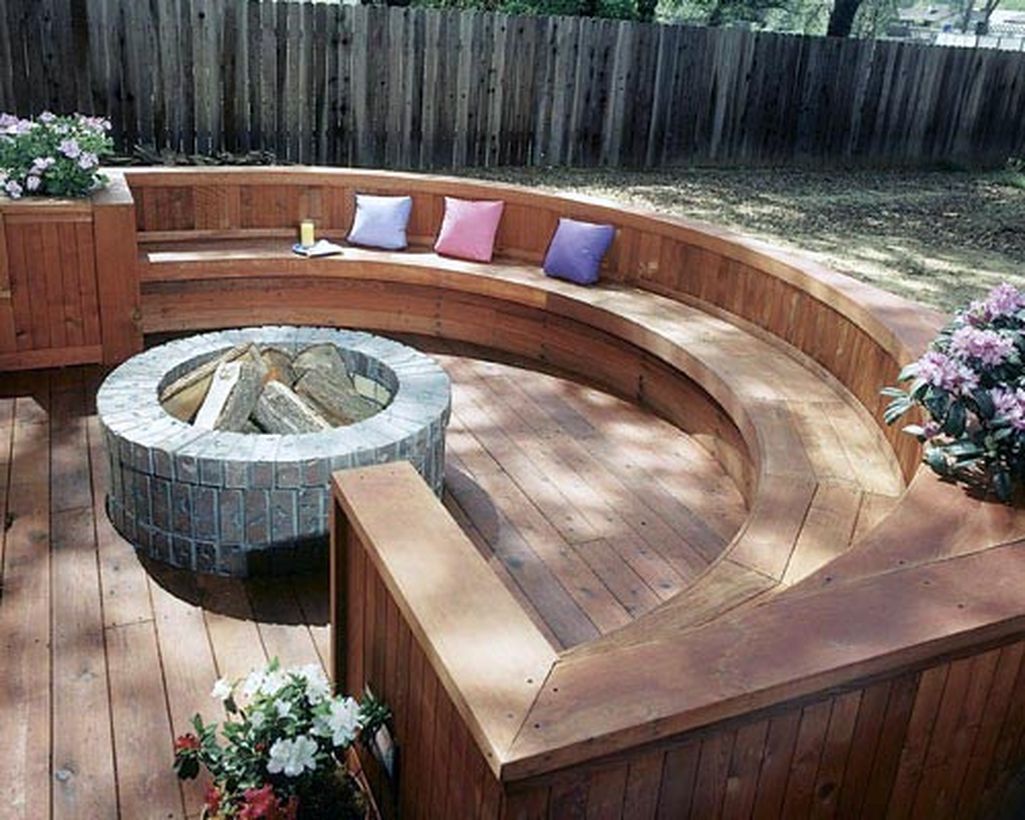 Backyard-patio-deck-design-with-brick-fire-pit-and-curved-wooden-bench-for-relaxing-with-family
