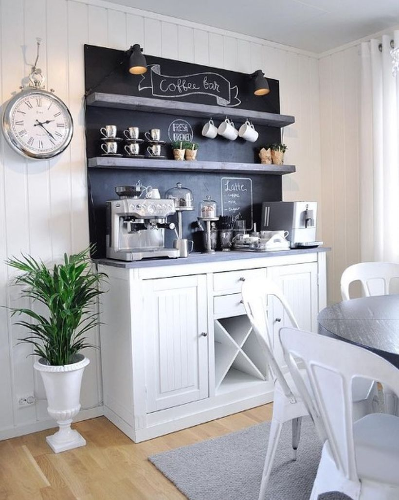 White coffee bar with black board, black shelf and added green plants in a white pot