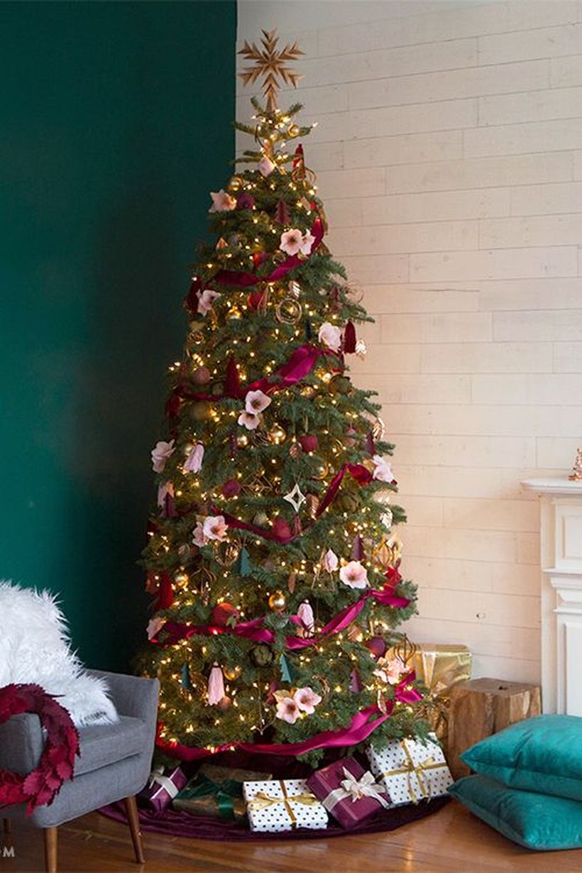Green-christmas-tree-with-gold-bell-ornament-white-flower-ornament-and-wrapped-in-pink-magenta-fabric-to-decorate-the-tree-to-look-beautiful