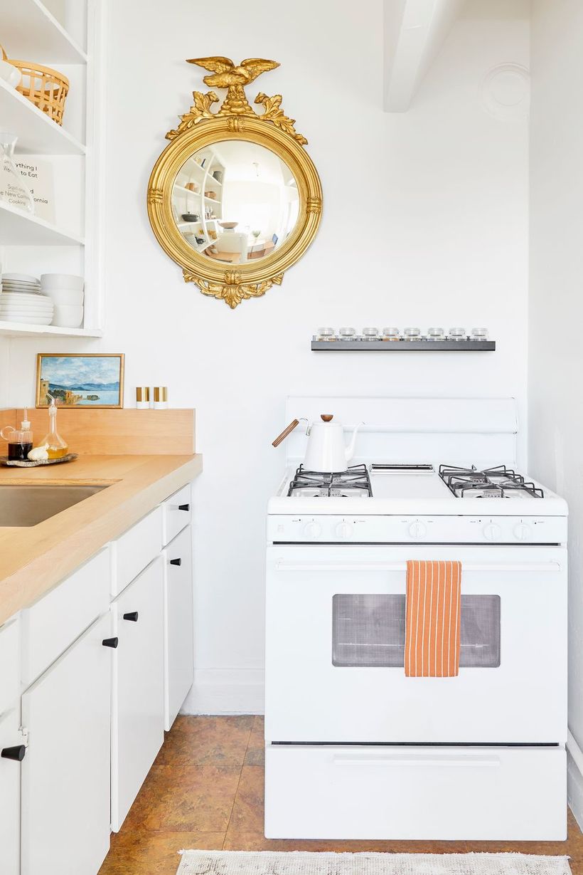 Minimalist-white-kitchen-design-with-modern-stove-and-round-gold-mirror-to-decorate-your-kitchen-in-the-small-space