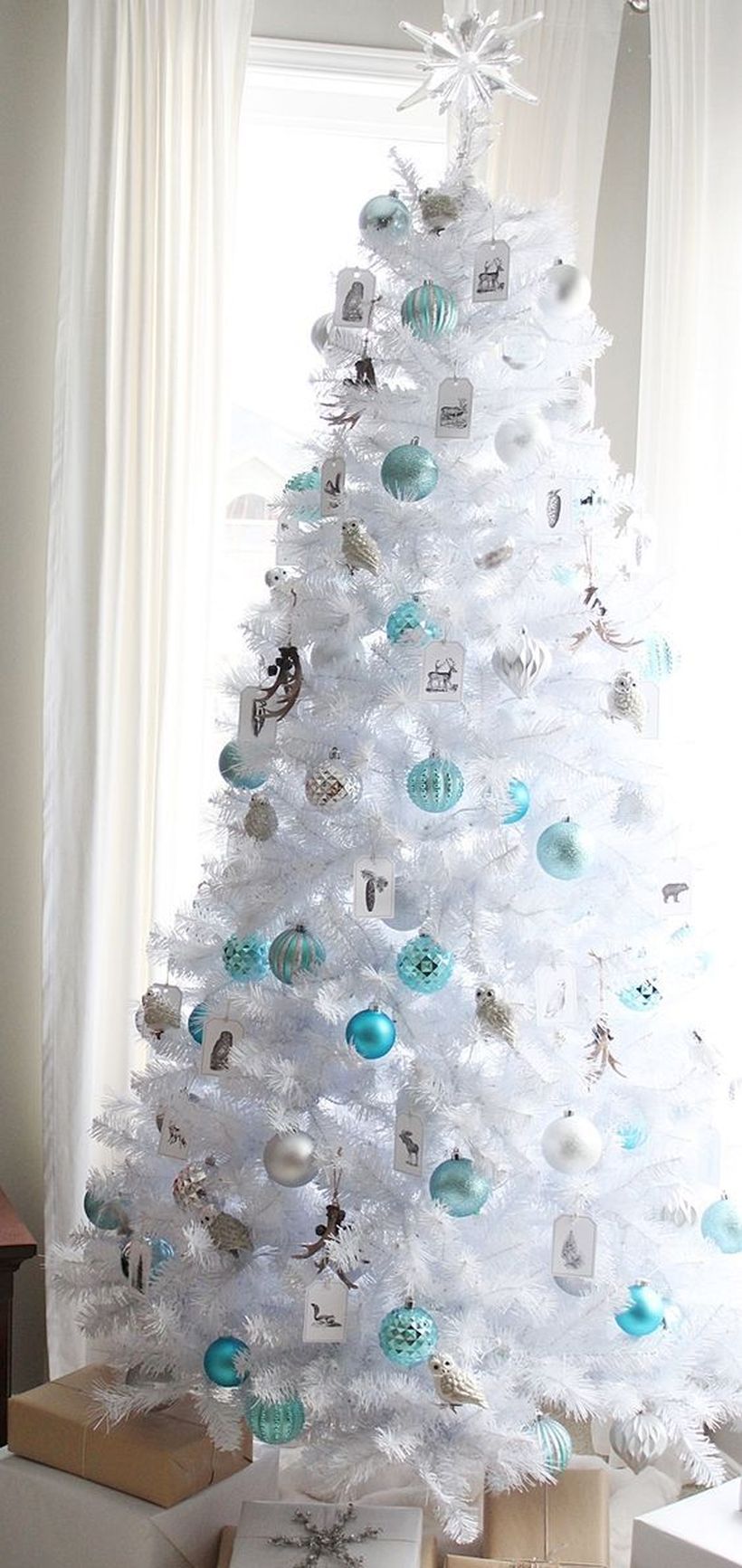 White-christmas-tree-decorated-in-blue-and-silver-bell-with-frost-and-star-ornament-at-the-top