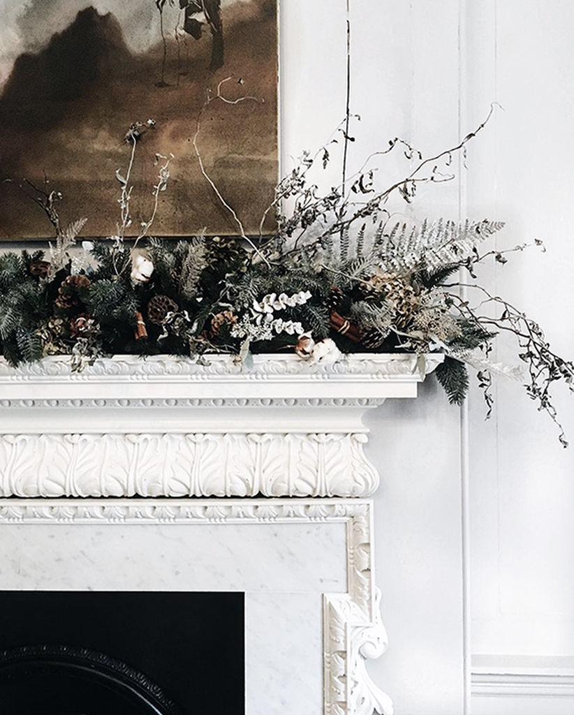 Neutral fireplace with branch and flowers above it