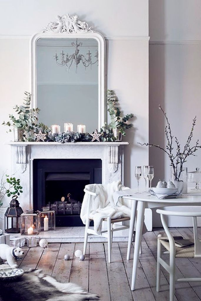 White fireplace wtih plants and big mirror above it