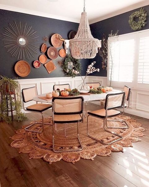 A-bright-boho-dining-room-with-a-beaded-chandelier-wicker-chairs-a-jute-rug-decorative-plates-and-greenery