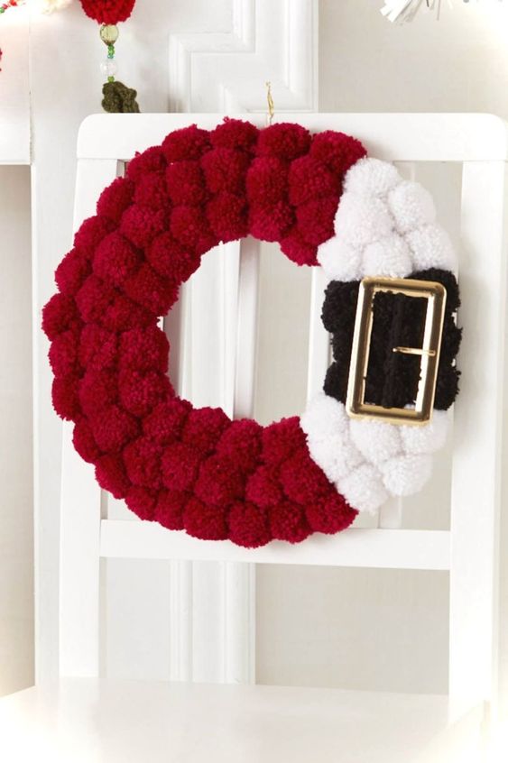 2-06-a-red-black-and-white-pompom-santa-inspired-wreath-with-a-large-buckle-is-a-fun-idea-instead-of-a-usual-greenery-one