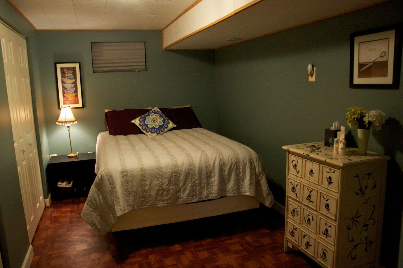 Traditional-dresser-and-wide-bed-inside-rustic-basement-bedroom-ideas-with-brown-flooring