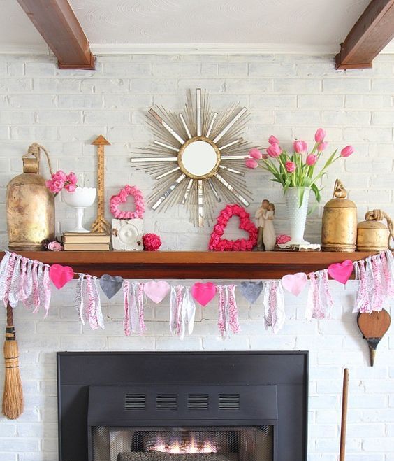 A-bright-and-white-valentine-mantel-with-a-heart-and-tassel-garland-pink-blooms-pink-hearts-and-gold-touches