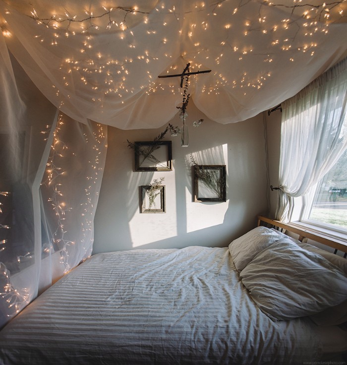 Baldachin-made-from-sheer-white-fabric-and-decorated-with-multiple-lit-string-lights-over-a-bed-teenage-bedroom-ideas-for-small-rooms-window-and-three-framed-bouquets-of-dried-flowers