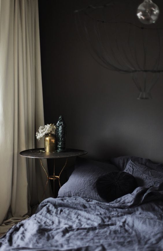 Black-walls-graphite-bedding-and-a-refined-nightstand-with-gold-legs