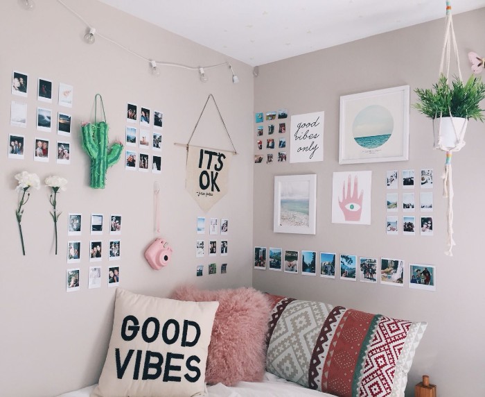 Framed-images-polaroid-photos-flowers-and-a-pink-camera-hanging-on-the-cream-walls-of-a-small-room-teen-bedrooms-pink-white-and-black-and-multicolored-cushions