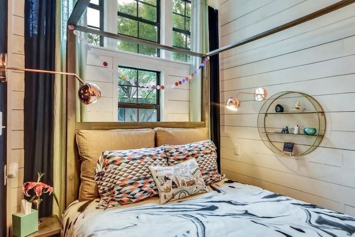 White-wooden-walls-with-small-metal-book-shelf-on-the-wall-colorful-throw-pillows-on-the-bed-tall-windows-teen-girl-room-decor