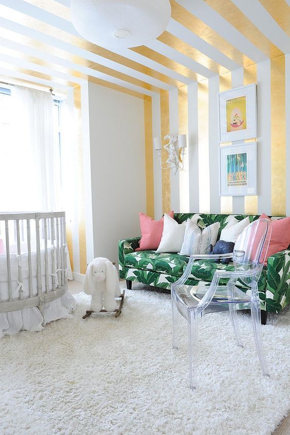 3-12-a-bright-nursery-with-a-glam-feel-a-striped-gold-and-white-wall-and-ceiling-a-tropical-leaf-print-sofa-and-an-acrylic-chair