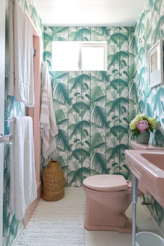A-bright-tropical-bathroom-with-tropical-wallpaper-a-pink-sink-and-toilet-neutral-linens
