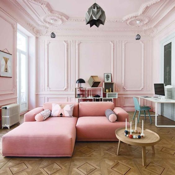 A-gorgeous-blush-living-room-with-molding-a-pink-sofa-a-creative-storage-unit-and-a-working-space-at-the-wall