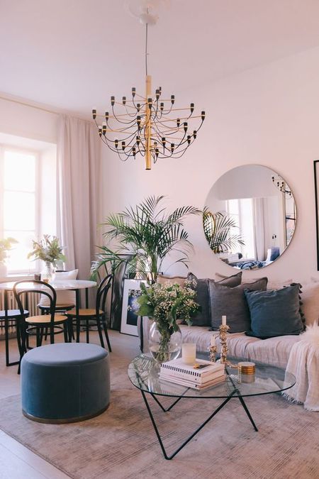 A-soft-living-dining-room-with-blush-walls-a-round-mirror-a-chic-chandelier-touches-of-grey-and-navy