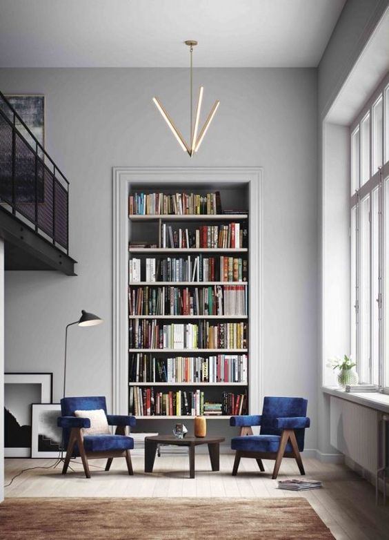 A-stylish-conversation-and-reading-nook-with-navy-velvet-chairs-a-large-built-in-bookshelf-unit-and-a-cool-chandelier-3