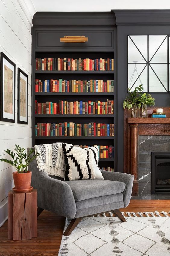 A-stylish-moody-space-with-dark-built-in-bookshelves-a-marble-fireplace-and-a-grey-chair-for-much-comfort-3