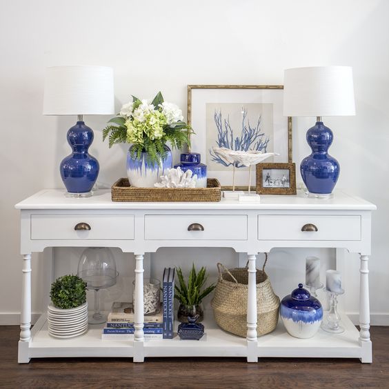 112-a-white-vintage-console-with-bold-blue-lamps-and-vases-plants-in-pots-baskets-and-corals