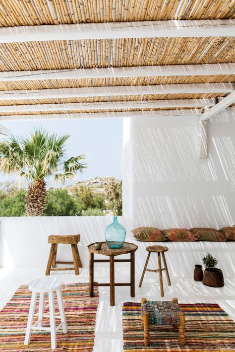 2-12-a-tropical-terrace-with-colorful-boho-rugs-wooden-stools-and-a-table-some-pillows-and-potted-grreenery