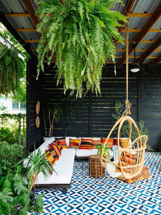 2-15-a-beautiful-tropical-patio-with-a-roof-and-greenery-hanging-down-with-an-l-shaped-sofa-with-colorful-pillows-a-rattan-chair-and-a-mosaic-tile-floor
