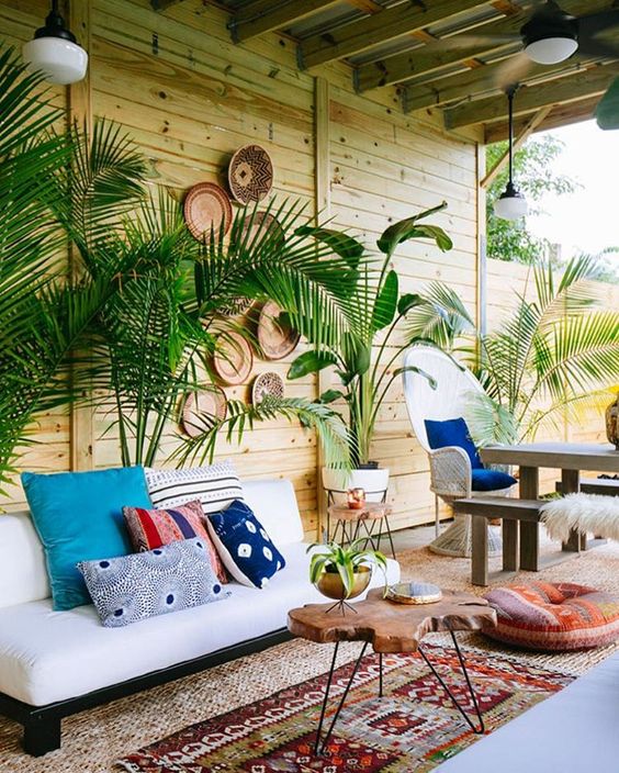 2-22-a-tropical-boho-patio-with-potted-plants-a-white-sofa-boho-rugs-and-an-ottoman-a-living-edge-table-and-decorative-baskets-on-the-wall