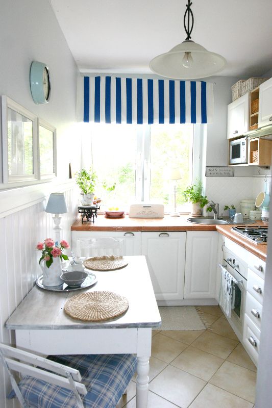 A-cozy-coastal-kitchen-with-white-cabinetry-bold-countertops-striped-and-plaid-textiles-and-a-pendant-lamps