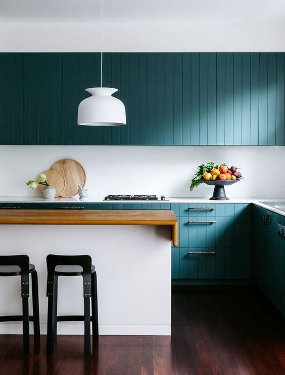 A-stunning-turquoise-coastal-kitchen-with-beadboard-cabinets-a-white-kitchen-island-with-a-stained-countertop-black-stools-and-a-white-pendant-lamp