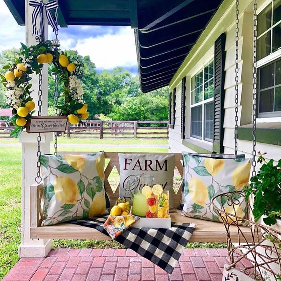1-a-summer-farmhouse-porch-with-a-hanging-bench-bright-citrus-print-pillows-a-citrus-wreath-and-some-drinks-on-a-tray