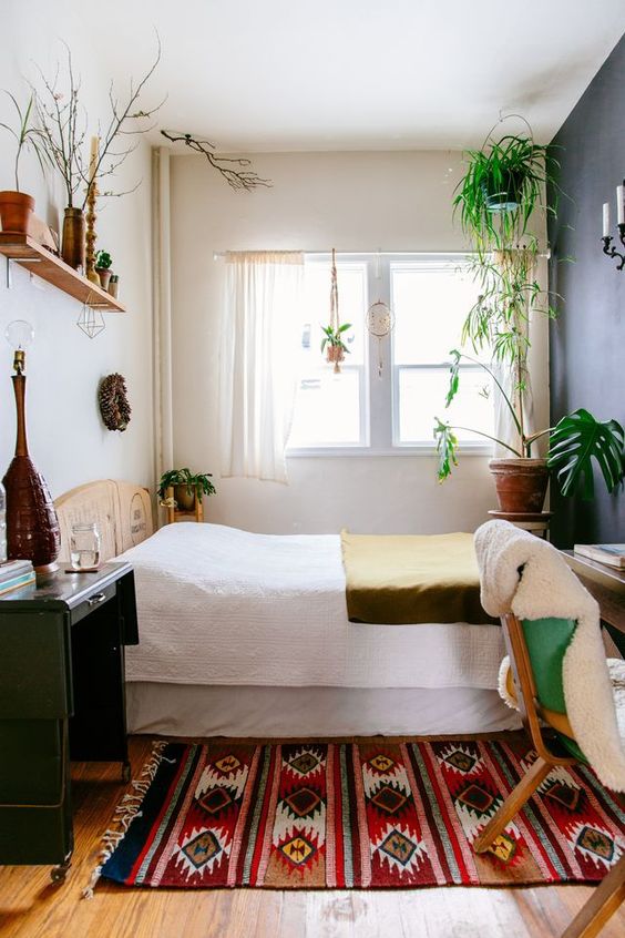 A-small-boho-bedroom-with-a-wooden-bed-desk-and-chair-boho-textiles-potted-plants-and-some-wicker-touches