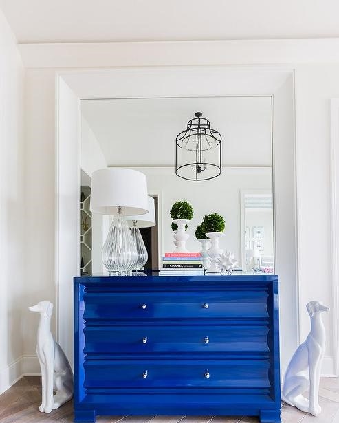 Foyer-mirrored-accent-wall-white-dalmatian-statues-blue-lacquered-chest