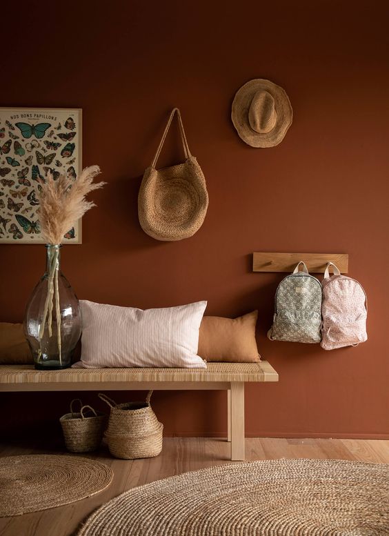 02-a-boho-entryway-with-a-terracotta-wall-a-woven-bench-and-a-rack-some-baskets-and-pampas-grass-in-a-large-bottle