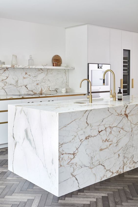 09-a-modern-luxurious-kitchen-with-white-cabinets-a-white-marble-kitchen-island-and-a-backsplash-plus-gold-fixtures