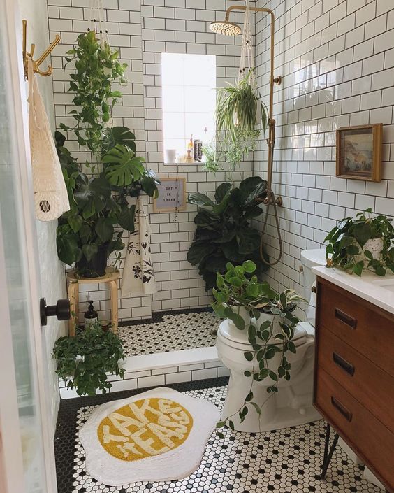 2-a-small-and-neutral-bathroom-with-a-wooden-vanity-lots-of-greenery-in-pots-and-some-suspended-plants